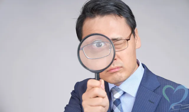 虫眼鏡を覗き込む男性